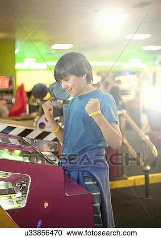 Stock Image - Boy celebrating success in amusement arcade. Fotosearch