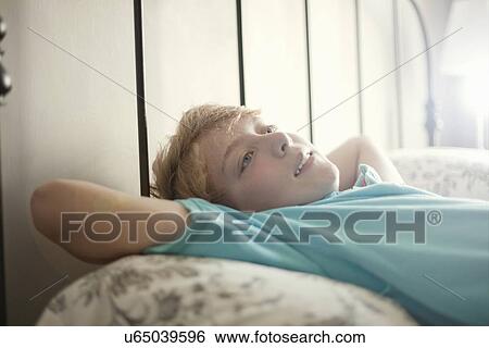 Boy relaxing on bed daydreaming View Large Photo Image Stock Photograph - Boy relaxing on bed daydreaming. Fotosearch