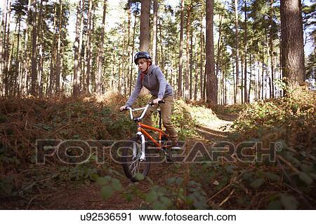 Stock Image - Boy riding his BMX in forest. Fotosearch