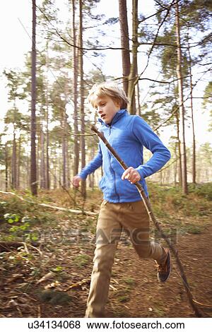 Stock Photo - Boy running with a stick in woods. Fotosearch