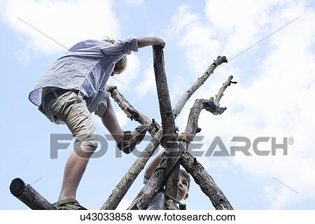 Stock Photo - Boys climbing branch structure. Fotosearch