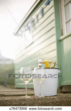 Stock Photograph - Bucket with wine and glasses outside beach hut. Fotosearch