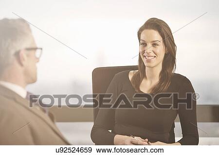 Stock Photo - Business colleagues chatting at desk in office. Fotosearch