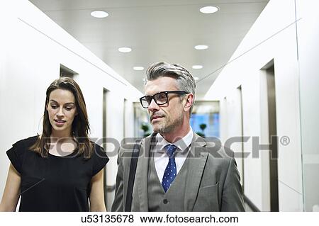 Business colleagues walking along office corridor View Large Photo Image Stock Photo - Business colleagues walking along office corridor. Fotosearch