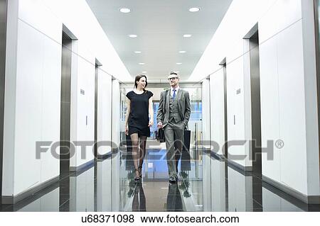 Stock Photo - Business partners walking along office corridor. Fotosearch