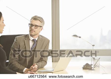 Picture - Businessman interviewing young female candidate in office. Fotosearch