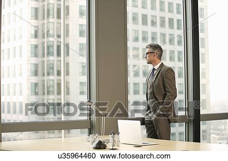 Businessman looking out of office window View Large Photo Image Stock Image - Businessman looking out of office window. Fotosearch