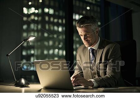 Businessman working late in office on laptop View Large Photo Image Stock Image - Businessman working late in office on laptop. Fotosearch