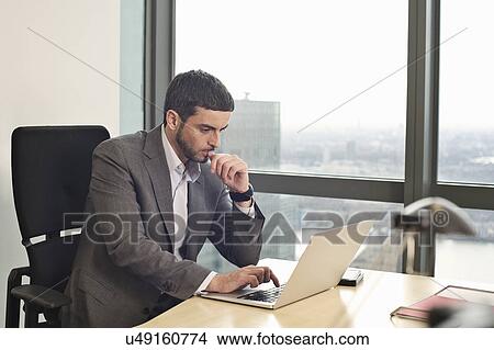 Businessman working on laptop in office View Large Photo Image Picture - Businessman working on laptop in office. Fotosearch