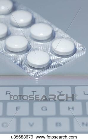 Stock Photo - Buying drugs online. Blister pack containing 250-mg Erythromycin tablets on the screen of a tablet computer. Fotosearch