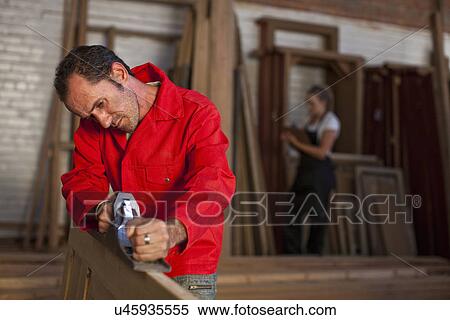 Stock Photography - Carpenter using plane. Fotosearch