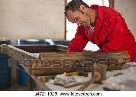 Stock Photo - Carpenter working on wooden frame. Fotosearch