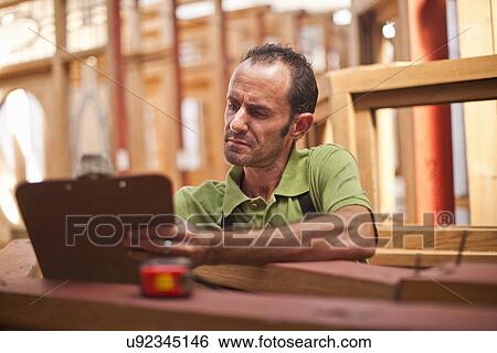 Carpenter writing on clipboard View Large Photo Image Stock Photograph - Carpenter writing on clipboard. Fotosearch