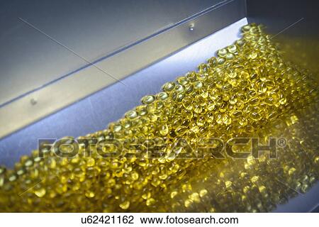 Stock Image - Close up of capsules in packing machine in pharmaceutical factory. Fotosearch
