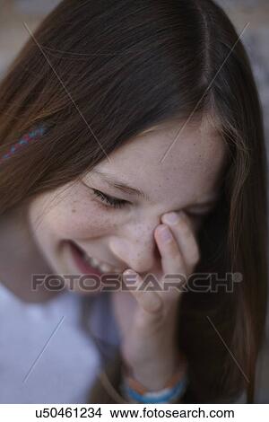 Picture - Close up of giggling girl with her head down. Fotosearch
