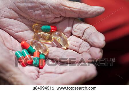 Stock Photography - Close up of senior woman's hands holding pills. Fotosearch