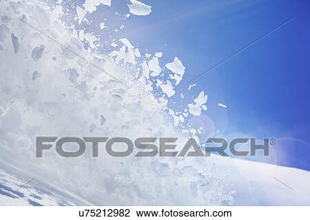 Stock Image - Close up of snow covered hill with powder snow and ice mid air. Fotosearch