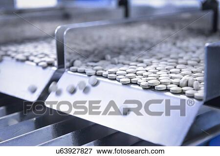 Stock Photo - Close up of tablets in packing machine in pharmaceutical factory. Fotosearch