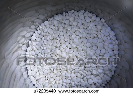 Stock Image - Close up of tablets in stainless steel drum in pharmaceutical factory. Fotosearch