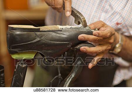 Stock Photo - Cobbler mending sole of shoe. Fotosearch