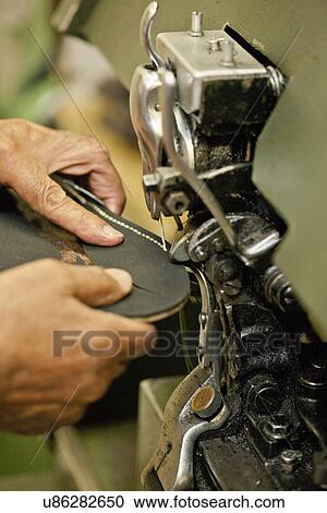 Stock Image - Cobbler sewing sole of boot. Fotosearch