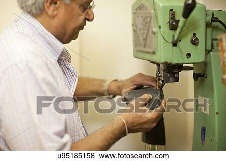 Stock Photo - Cobbler sewing sole of boot. Fotosearch
