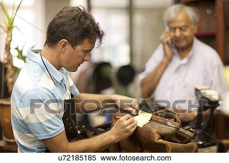 Cobbler writing on adhesive note View Large Photo Image Stock Photography - Cobbler writing on adhesive note. Fotosearch