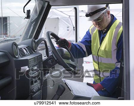 Stock Image - Emergency Response Team worker looking at notes in four wheel drive vehicle. Fotosearch