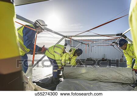 Stock Image - Emergency Response Team workers erecting tent control centre. Fotosearch