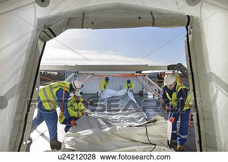 Stock Photo - Emergency Response Team workers erecting tent control centre. Fotosearch