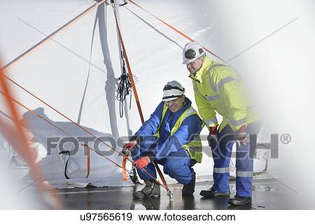 Stock Photo - Emergency Response Team workers erecting tent control centre. Fotosearch