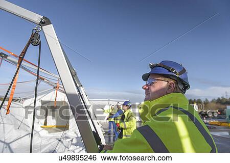 Stock Photograph - Emergency Response Team workers erecting tent control centre. Fotosearch