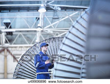 Stock Photograph - Engineer inspecting steam turbine in repair bay. Fotosearch