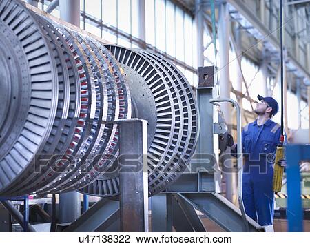 Stock Image - Engineer lifting high pressure steam turbine with crane in workshop. Fotosearch