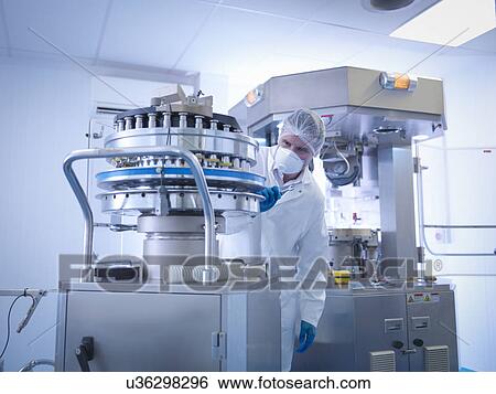 Stock Photograph - Engineer performing maintenance on tablet manufacturing machine in pharmaceutical factory. Fotosearch