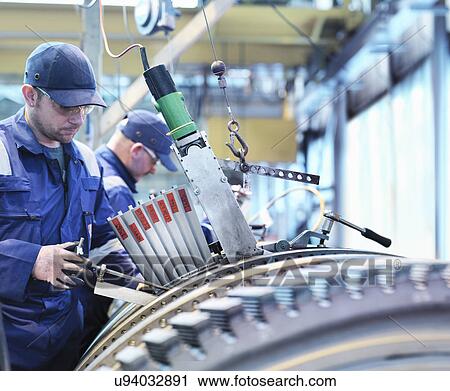 Stock Image - Engineers fitting blades to steam turbine in turbine repair works. Fotosearch