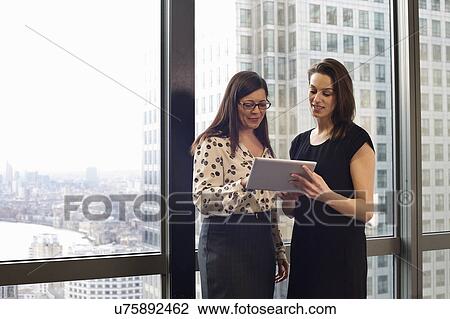 Female business colleagues looking at digital tablet in office View Large Photo Image Stock Image - Female business colleagues looking at digital tablet in office. Fotosearch