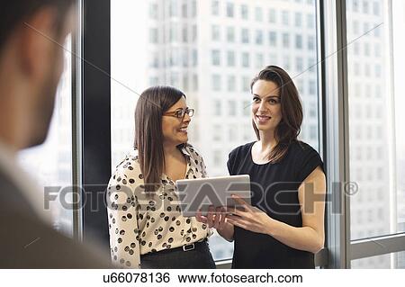 Stock Photograph - Female business colleagues using digital tablet in office. Fotosearch