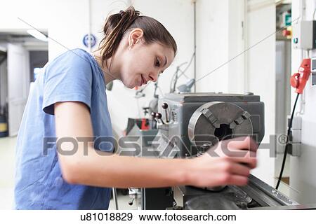 Stock Photo - Female engineer checking machine in workshop. Fotosearch