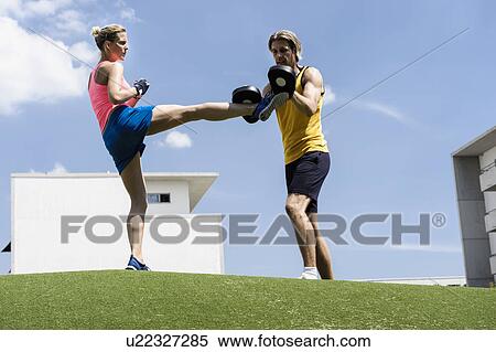 Stock Photography - Female kick boxer and personal trainer in park. Fotosearch