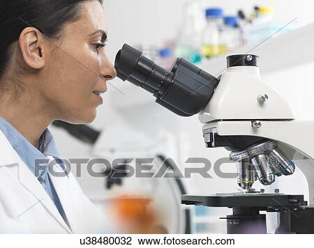 Stock Image - Female scientist viewing sample slide for clinical test in laboratory. Fotosearch