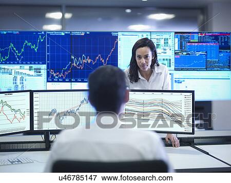 Stock Photo - Financial analysts looking at screens in control room. Fotosearch