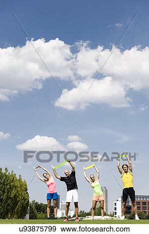 Stock Photo - Four people training with rubber exercise bands in park. Fotosearch