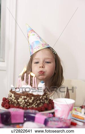 Stock Image - Girl blowing out candles on her birthday cake. Fotosearch