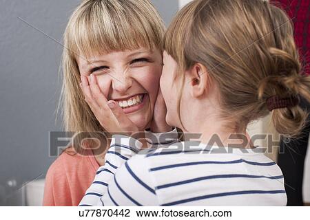 Stock Image - Girl cupping young woman's face. Fotosearch