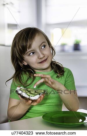 Stock Image - Girl dipping her finger in an open sandwich. Fotosearch