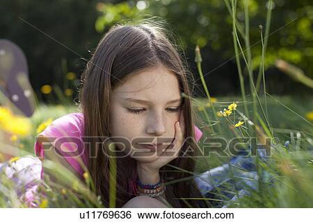 Girl lying in grass daydreaming View Large Photo Image Stock Photograph - Girl lying in grass daydreaming. Fotosearch