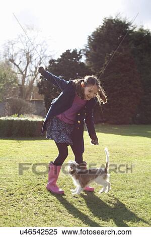Stock Photography - Girl playing in the garden with her pet dog. Fotosearch