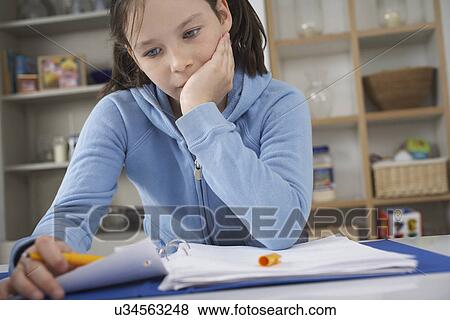 Girl sitting at kitchen counter struggling with homework View Large Photo Image Stock Photo - Girl sitting at kitchen counter struggling with homework. Fotosearch