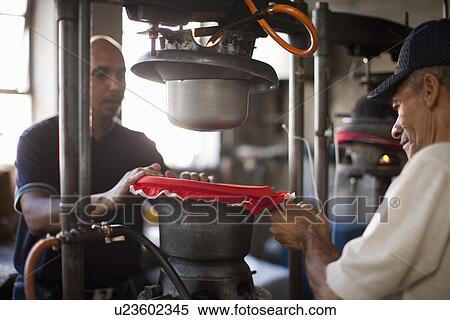 Stock Photography - Hat makers stretching fabric on mould in workshop. Fotosearch